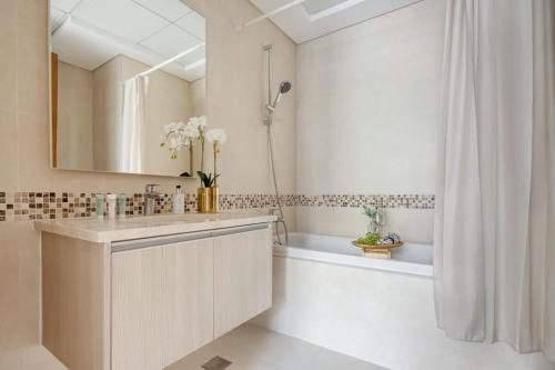 ein Badezimmer mit einem Waschbecken, einer Badewanne und einem Spiegel in der Unterkunft Frank Porter - Ansam Building 1 - Yas Island in Abu Dhabi
