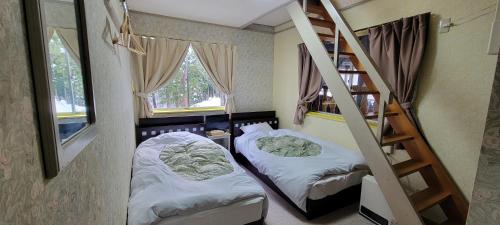 um pequeno quarto com duas camas e uma escada em ロッジＴＯＮＢＯ・石打 em Minami Uonuma
