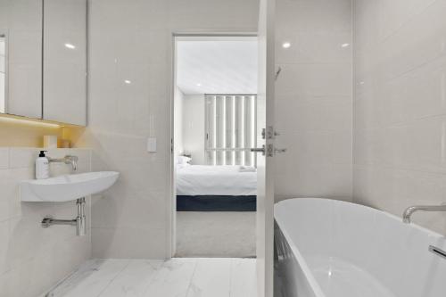 y baño blanco con lavabo y bañera. en Spectacular City & Harbour Views: Bondi Junction, en Sídney