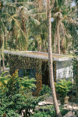 a building with palm trees in front of it at Homestay Bến Tre in Ben Tre