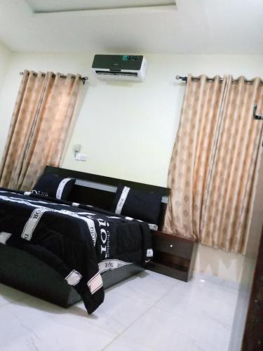 two beds in a room with curtains and a tv at F&B Service Apartment in Abeokuta