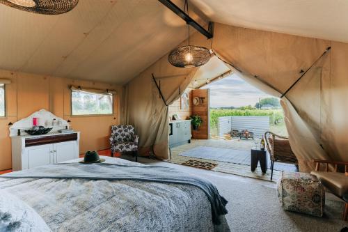 1 dormitorio en una tienda de campaña con 1 cama y cocina en Villas & Vines Glamping, en Hastings