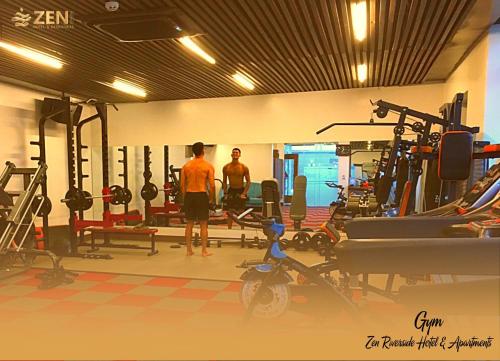 two men standing in a gym with machines at ZEN RIVERSIDE HOTEL & RESIDENCES in Hai Phong