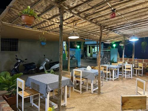 ein Restaurant mit Tischen und Stühlen unter einem Dach in der Unterkunft North & East Arambol I Goa in Arambol