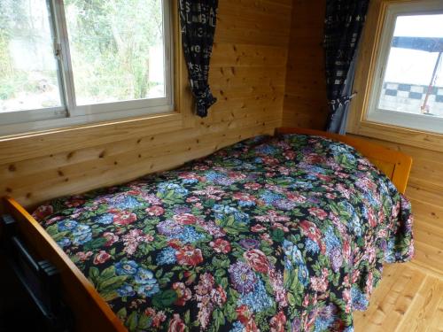 a bed in a room with a floral quilt on it at こや・かやき in Yufu