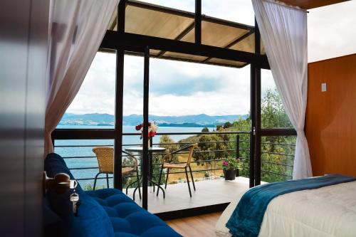 a bedroom with a view of the ocean from a balcony at Cabañas los Sauces in Tota
