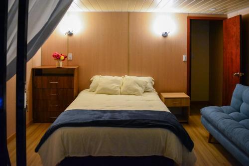 a bedroom with a bed and a blue couch at Cabañas los Sauces in Tota