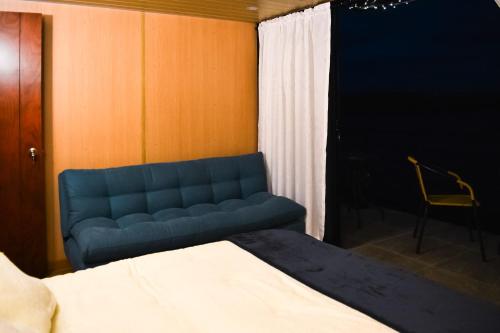 a blue couch in a bedroom with a bed at Cabañas los Sauces in Tota