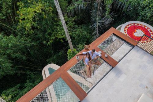 a man sitting on the edge of a swimming pool at Suara Alam Hotel Ubud by Ini Vie Hospitality in Ubud