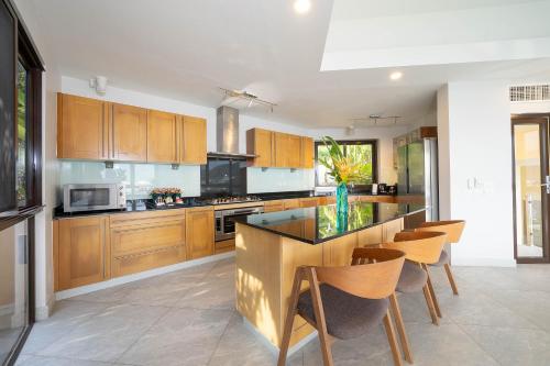 a kitchen with wooden cabinets and a island with chairs at IndoChine Resort and Villas in Patong Beach