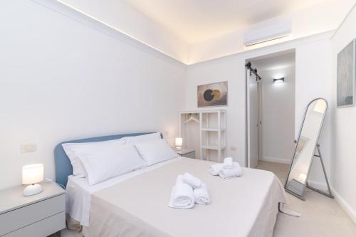 Habitación blanca con cama y espejo en Secret Garden House - Happy Rentals en Marina di Portisco