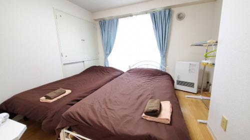 a bedroom with a bed with brown sheets and a window at 札幌市中心部大通公園まで徒歩八分観光移動に便利なロケーションe1007#17B in Sapporo