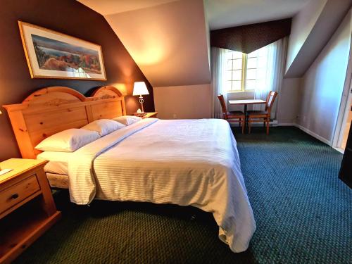 Un dormitorio con una gran cama blanca y una mesa en Hotel Alila en Saint-Sauveur-des-Monts