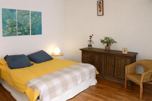 um quarto com uma cama com duas almofadas e uma cadeira em Le pied-à-terre du botaniste em Hauteville-Lompnes