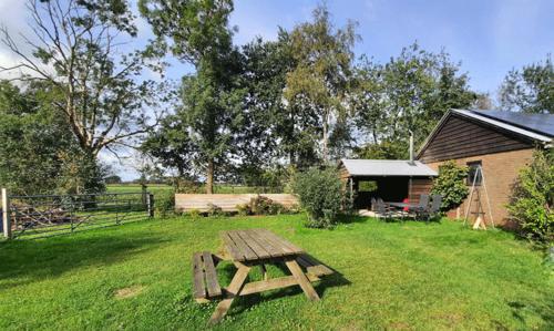 a wooden picnic table in the grass near a house at De Opkikker 10 persoons vakantiehuis met hottub in Giethoorn