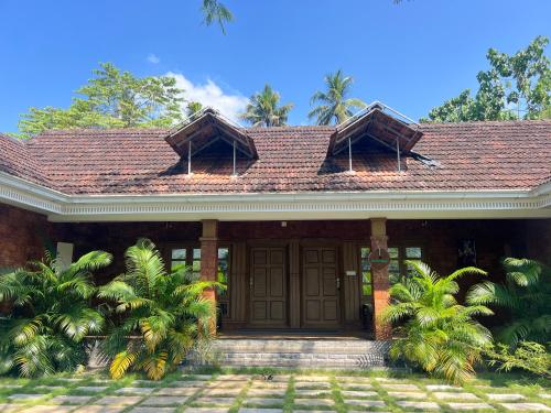 a house with a brown door and palm trees at Coconut Valley in Neriyamangalam