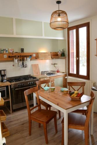 une cuisine avec une table en bois et des chaises ainsi qu'une salle à manger dans l'établissement Le pied-à-terre du botaniste, à Hauteville-Lompnes