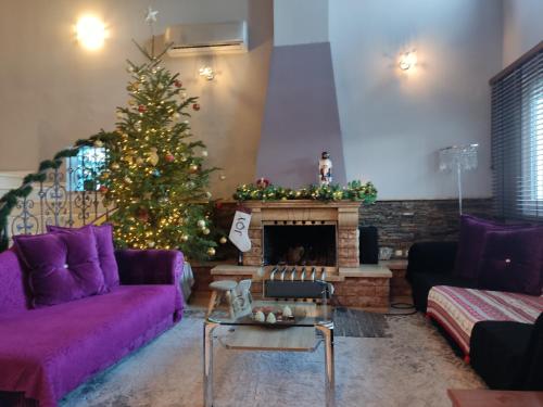 a living room with a christmas tree and a purple couch at Dana's Luxury Maisonette in Volos