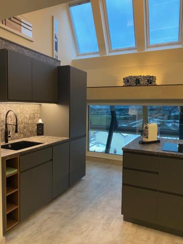 a kitchen with gray cabinets and a large window at Loft im Turm in Maishofen