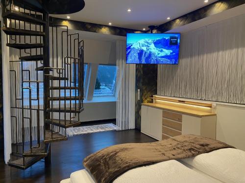 a bedroom with a staircase and a tv on the wall at Loft im Turm in Maishofen