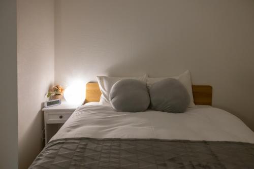 un letto con lenzuola e cuscini bianchi in una camera da letto di エイビル ad Osaka
