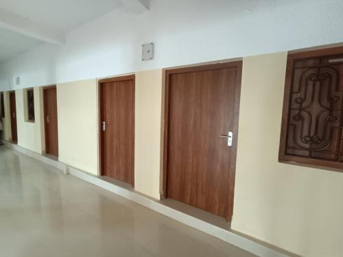 une rangée de portes en bois dans un couloir dans l'établissement OM KALYAN MANDAP, à Balāngīr