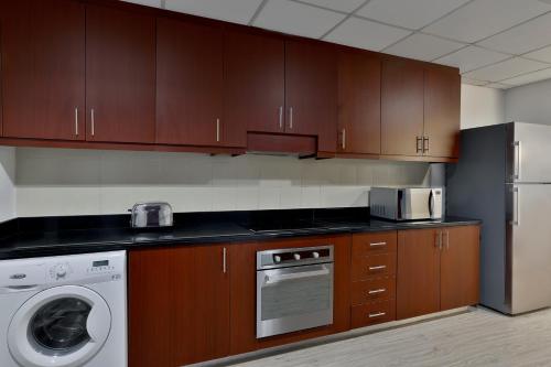 a kitchen with wooden cabinets and a washer and dryer at Hilton Dubai The Walk in Dubai
