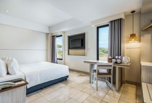 a hotel room with a bed and a desk at Swiss-Belcourt Lombok in Praya