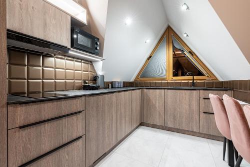 a kitchen with wooden cabinets and a window at Willa Trawers in Zakopane