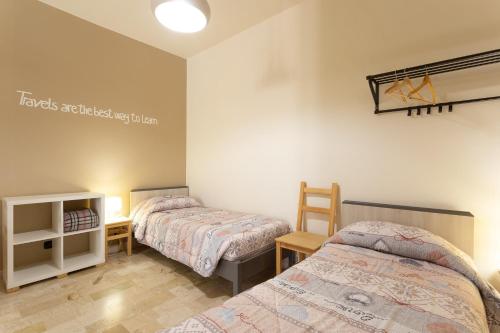 a bedroom with two beds and a table and a shelf at Pura Vida Barocca in Ragusa