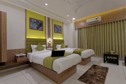 a hotel room with two beds with a laptop on them at HOTEL COMFY in Unjha