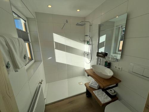 a white bathroom with a sink and a shower at Hotel Berghof in Berg im Drautal