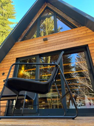 einen Stuhl vor einem Haus mit einem großen Fenster in der Unterkunft Viktorija chalet in Kopaonik