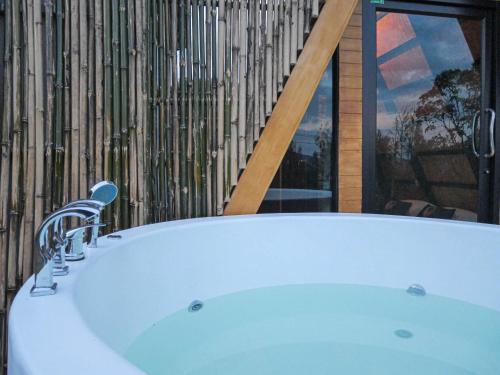 a bath tub in a bathroom with a window at RoomQuest Kid Tung Khao in Ban Huai Sok Noi