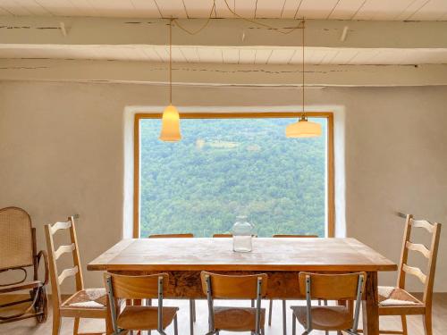 une table de salle à manger avec des chaises et une grande fenêtre dans l'établissement LA MAISON TREBUC, avec magnifique vue, à Montézic