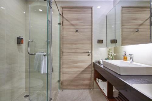 a bathroom with a sink and a glass shower at Adelphi Suites Bangkok - SHA Extra Plus in Bangkok