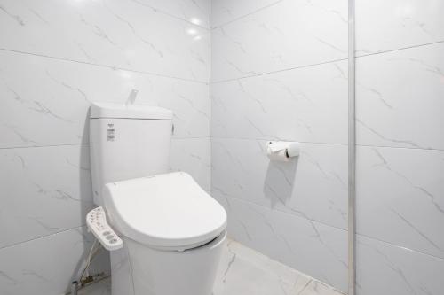 a white bathroom with a toilet with a remote control at glampark Kaiyokaku Aichi in Gamagori