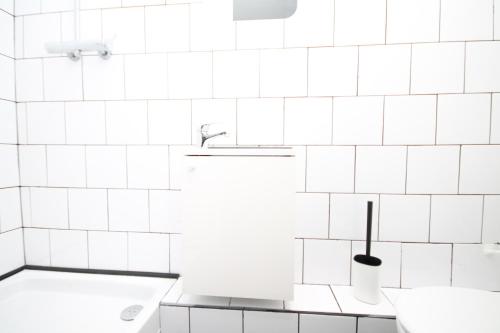 La salle de bains est pourvue de murs carrelés blancs et d'un lavabo. dans l'établissement 06 - Chambre avec TV proche Paris et transports WIFI, à Saint-Denis