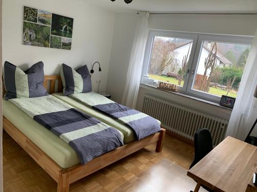a bedroom with a bed and a table and two windows at Ferienappartement Albschätzle 