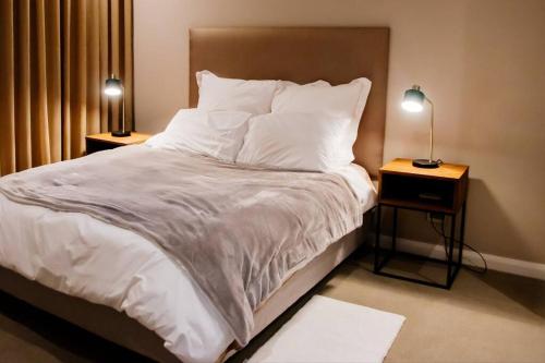 una camera da letto con un letto con lenzuola bianche e due lampade di 408 Trilogy ! EXCELLENT LOCATION ! Menlyn Maine a Pretoria