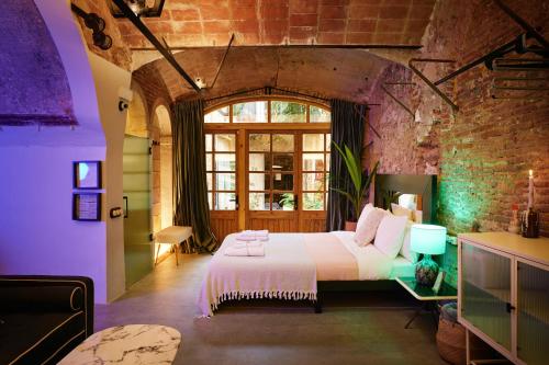 1 dormitorio con cama y pared de ladrillo en Dormsy aparthotel House en Arenys de Mar