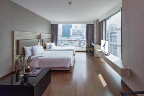 a hotel room with a bed and a large window at Adelphi Suites Bangkok - SHA Extra Plus in Bangkok