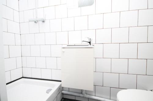 La salle de bains est pourvue de carrelage blanc, de toilettes et d'un lavabo. dans l'établissement 07 - Chambre proche Paris et Transports avec TV WIFI, à Saint-Denis
