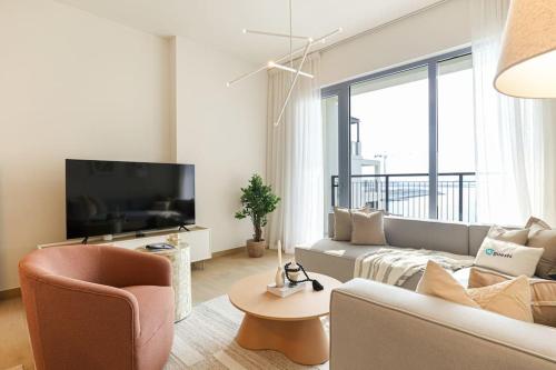 a living room with a couch and a tv at HiGuests - Dream stay in our Cozy 2BR in La Rive Community in Dubai