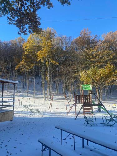 a park with two swings and benches in the snow at B&B Snow Village Roccaraso in Roccaraso