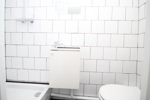 a white tiled bathroom with a toilet and a sink at 08 - Chambre proche Paris et Transports avec TV WIFI in Saint-Denis