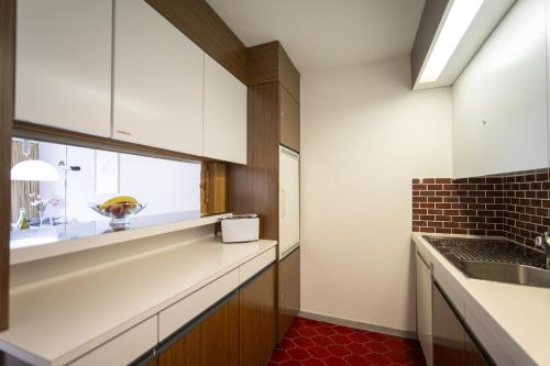 una cocina con armarios blancos y una ventana en Brentschpark 28, en Scuol