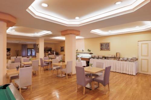 a restaurant with tables and chairs in a room at Louvre Hotel in Gouvia