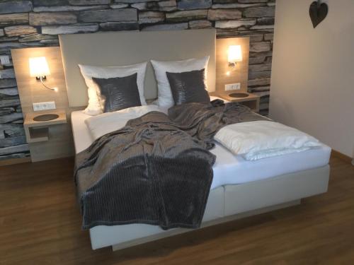 a bedroom with a white bed with a stone wall at Weingut Bastian in Brauneberg