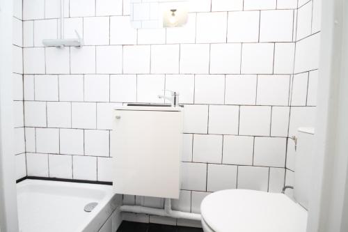 a white tiled bathroom with a toilet and a tub at 09 - Chambre proche Paris et Transports avec TV WIFI in Saint-Denis